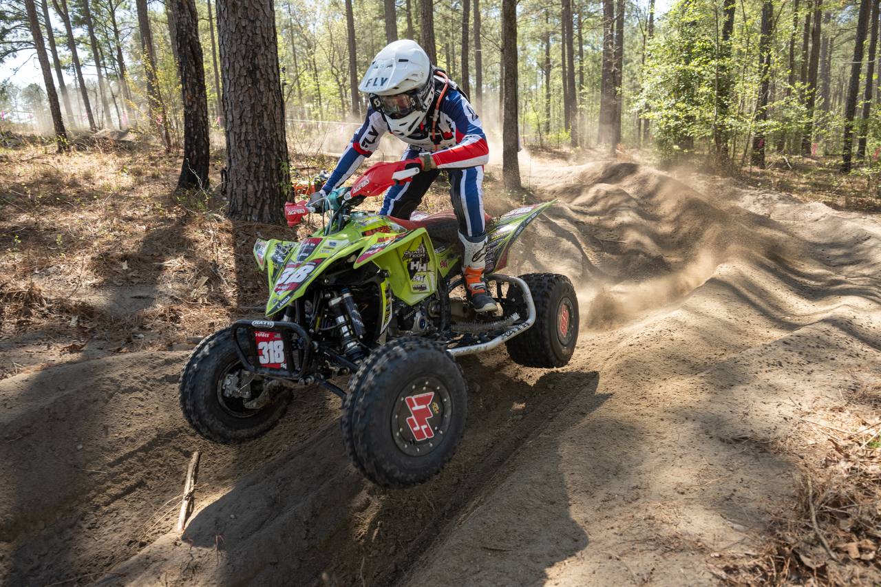 Rider clearing a sandy rhythm section in the pines