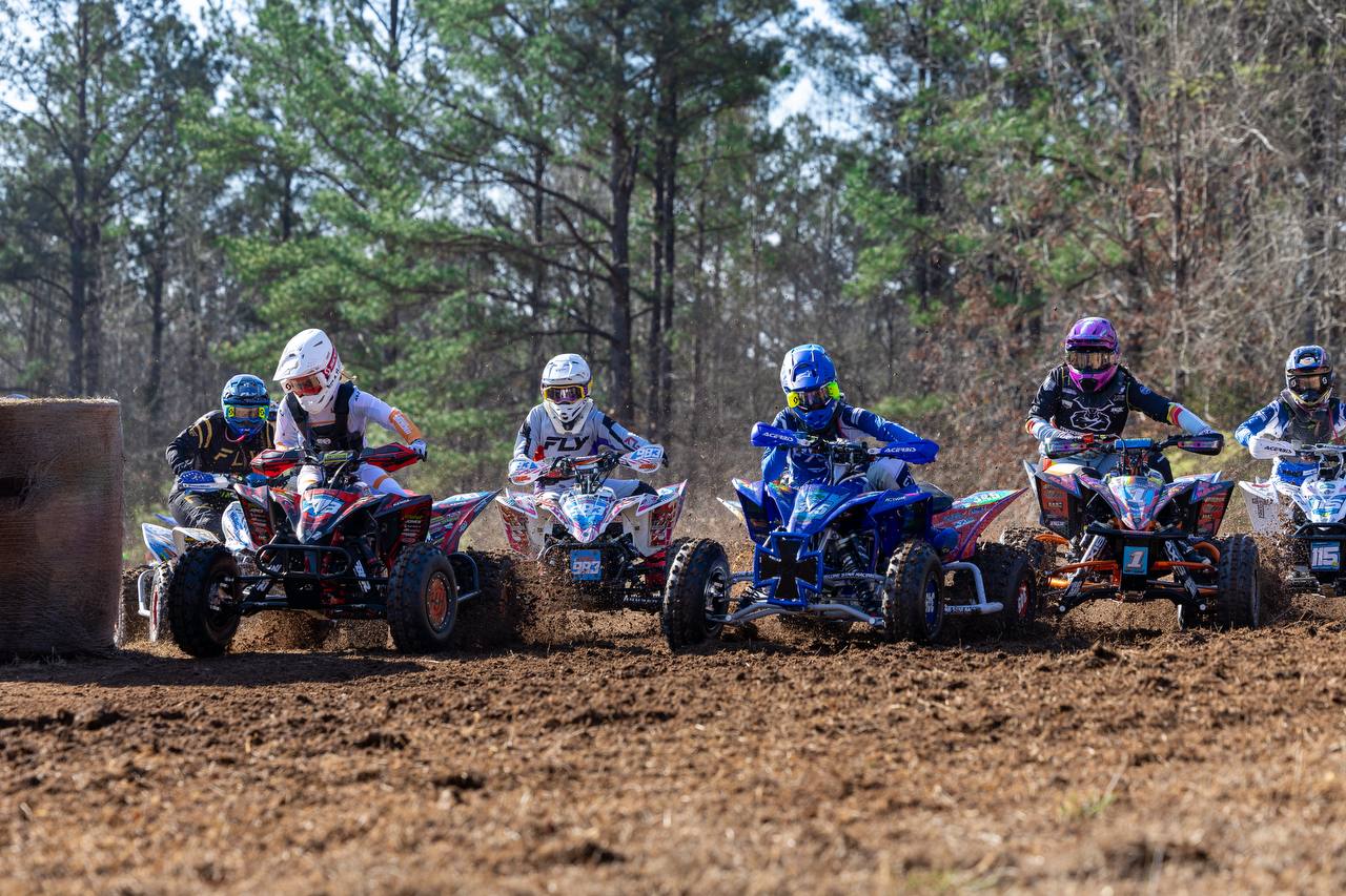 Rider smiling on the podium with trophy and holeshot award